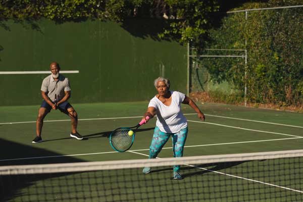 Male and Female playing tennis on same side of the court