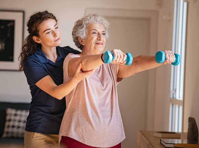 Elder woman with trainer using hand weights