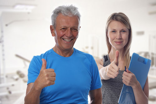 Senior aged male with female trainer with thumbs up