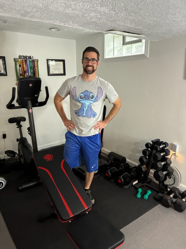 An ElderFIT trainer pictured standing in a home gym illustrates his availability to provide personal training for seniors in Cleveland.