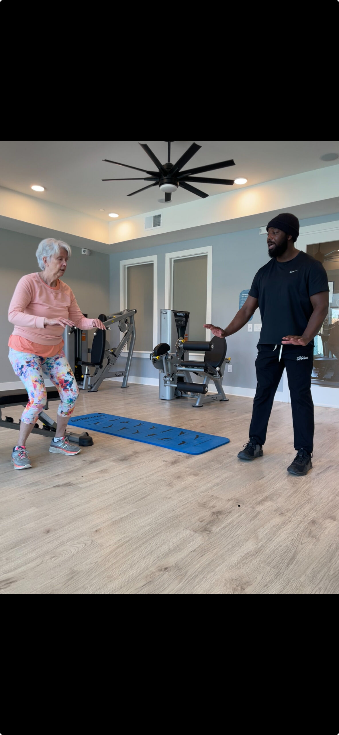 Picture of Michael an ElderFIT personal trainer for seniors in Frisco helping a senior female customer in a small gym