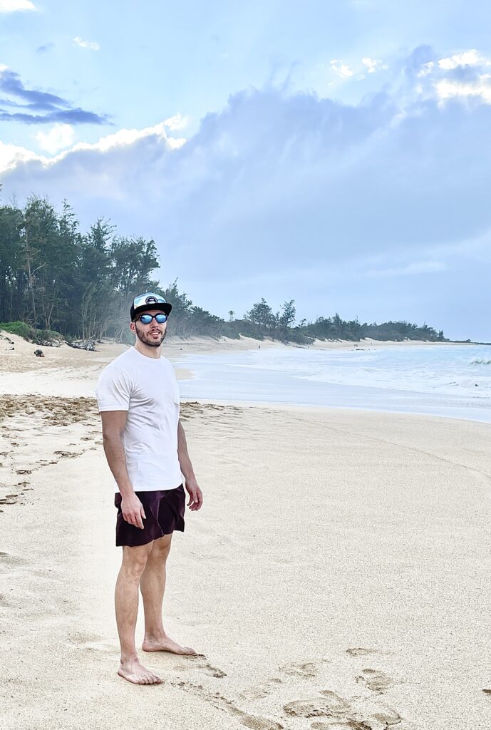 ElderFIT personal trainer for seniors in Santa Monica and Marina Del Rey is standing on a beach looking at camera with a baseball cap and sunglasses.