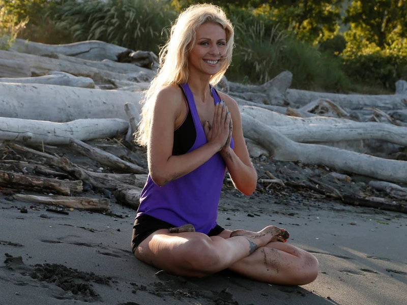 Picture of Shannon, an ElderFIT personal trainer for seniors in Seattle sitting in front of a stream in a yoga mediation pose